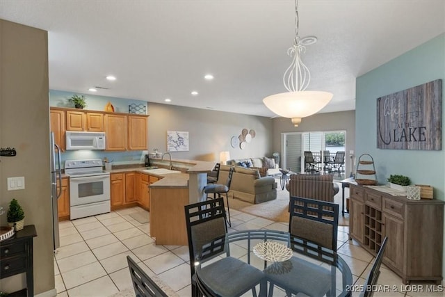 kitchen with light tile patterned flooring, sink, hanging light fixtures, kitchen peninsula, and white appliances