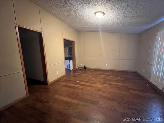 unfurnished room with dark hardwood / wood-style floors and a textured ceiling