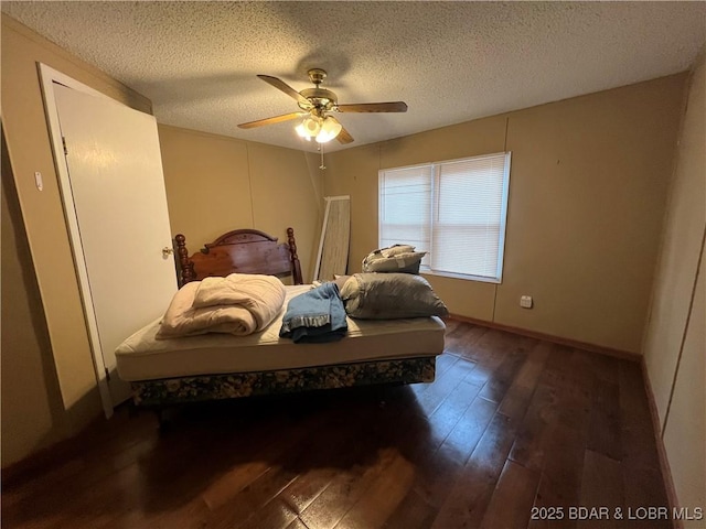 bedroom with ceiling fan, dark wood-type flooring, and a textured ceiling