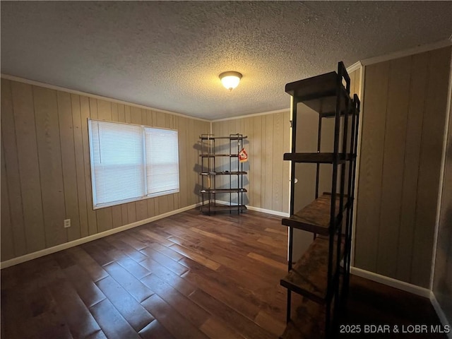 empty room featuring dark wood-type flooring, ornamental molding, and a textured ceiling