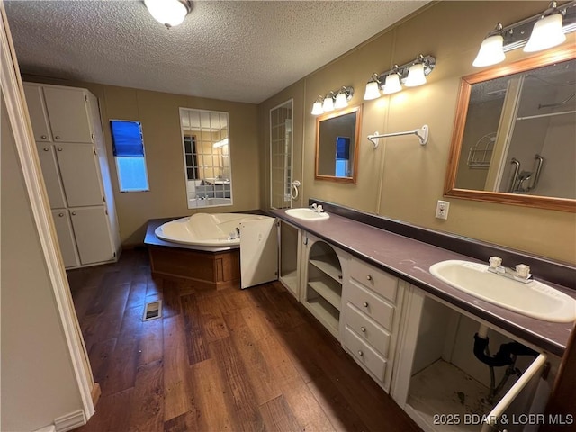 bathroom with hardwood / wood-style flooring, vanity, a textured ceiling, and a tub to relax in