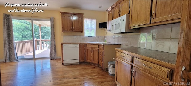 kitchen featuring sink, white appliances, light hardwood / wood-style floors, and backsplash