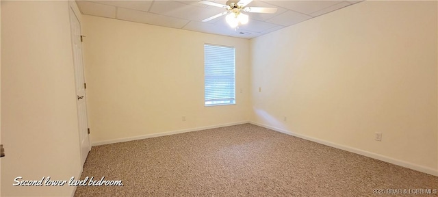 carpeted spare room featuring a drop ceiling and ceiling fan