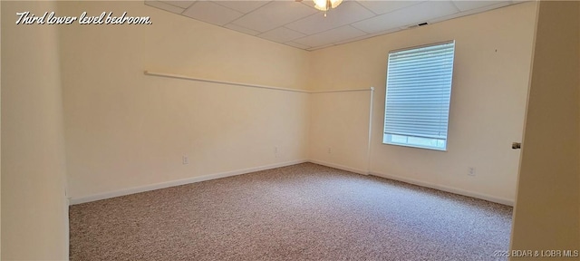 carpeted spare room featuring a paneled ceiling