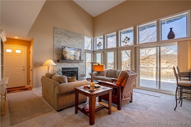 carpeted living room with a high ceiling and a stone fireplace