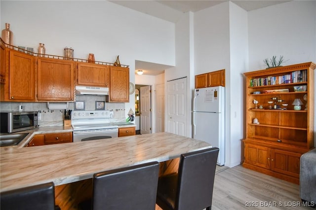 kitchen with tasteful backsplash, butcher block counters, white appliances, and kitchen peninsula