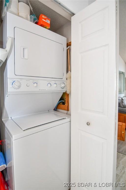 clothes washing area with stacked washer / dryer