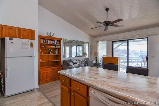 kitchen featuring lofted ceiling, ceiling fan, light hardwood / wood-style floors, a textured ceiling, and white fridge