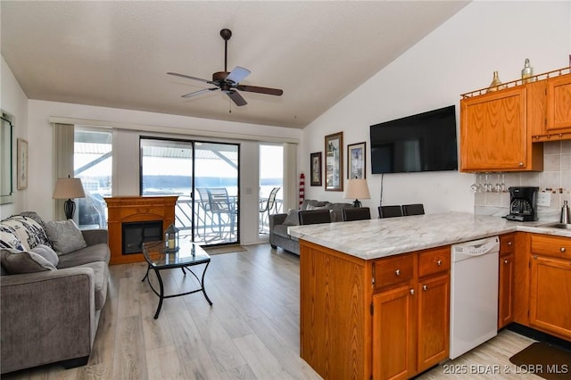 kitchen featuring a healthy amount of sunlight, white dishwasher, kitchen peninsula, and vaulted ceiling