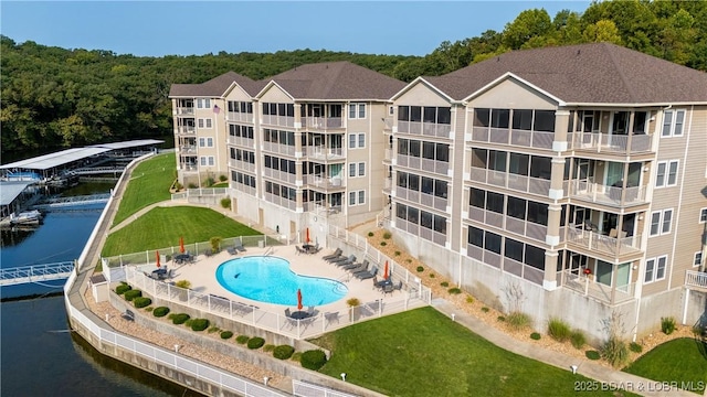 view of swimming pool featuring a water view, a yard, and a patio area