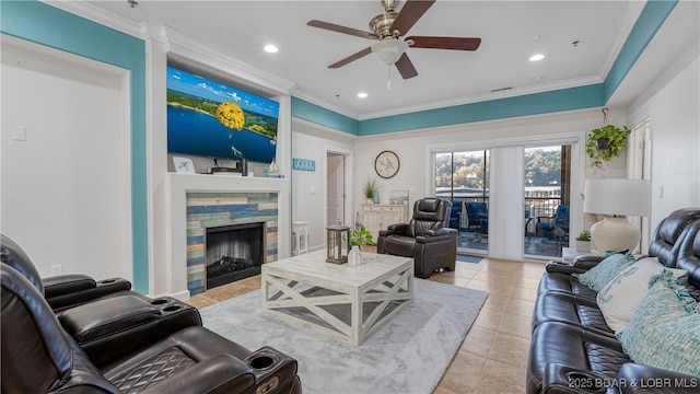 living room with light tile patterned floors, a stone fireplace, ornamental molding, and ceiling fan