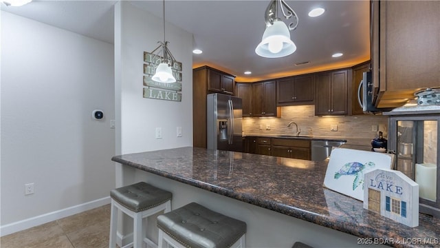 kitchen featuring dark brown cabinetry, stainless steel appliances, decorative light fixtures, and sink