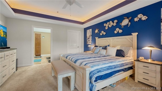 carpeted bedroom with a tray ceiling, ornamental molding, and ceiling fan