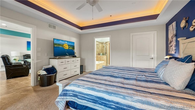 bedroom with crown molding, ceiling fan, connected bathroom, a tray ceiling, and light colored carpet