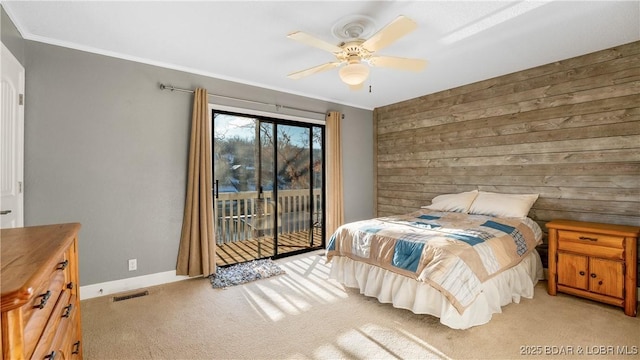 carpeted bedroom featuring ornamental molding, access to outside, ceiling fan, and wooden walls