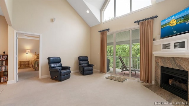 sitting room with light carpet, high vaulted ceiling, and a premium fireplace