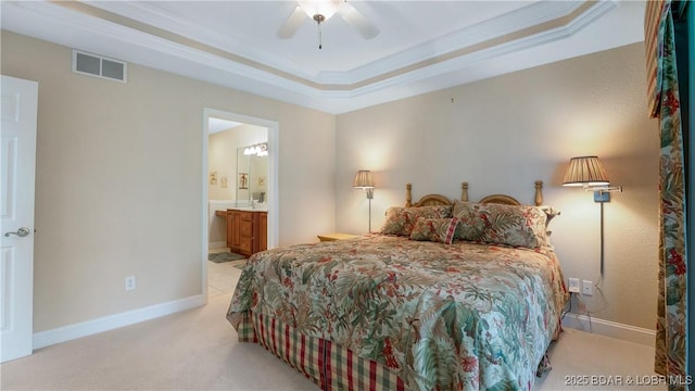 carpeted bedroom with a raised ceiling, ornamental molding, connected bathroom, and ceiling fan