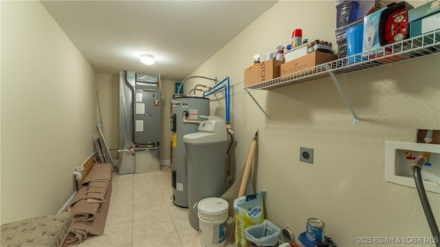 washroom with electric dryer hookup, hookup for a washing machine, heating unit, a textured ceiling, and tile patterned floors