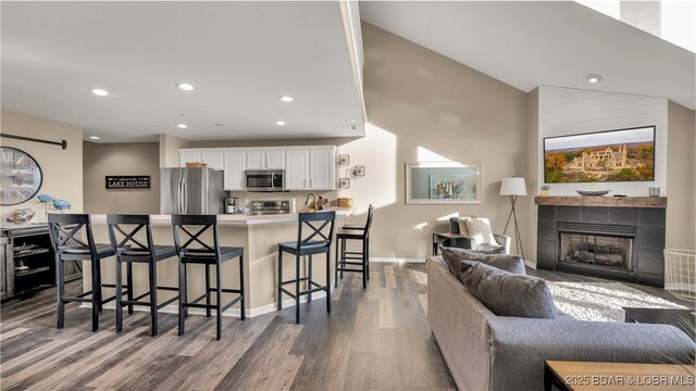 kitchen featuring hardwood / wood-style flooring, appliances with stainless steel finishes, a kitchen breakfast bar, white cabinets, and kitchen peninsula