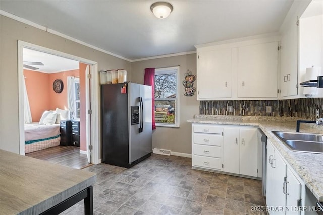 kitchen featuring sink, white cabinetry, crown molding, appliances with stainless steel finishes, and backsplash