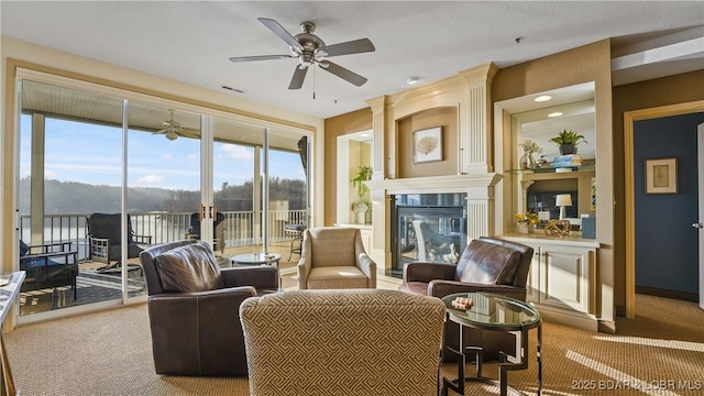 carpeted living room featuring ceiling fan and a fireplace