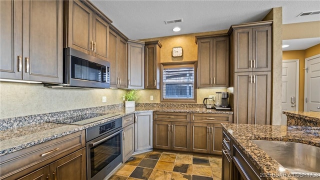 kitchen with dark stone countertops, a textured ceiling, and appliances with stainless steel finishes