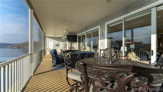 sunroom with a water view and ceiling fan