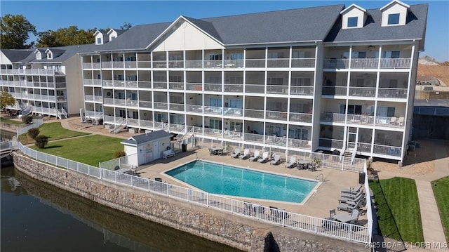 pool featuring a water view, fence, and a patio area