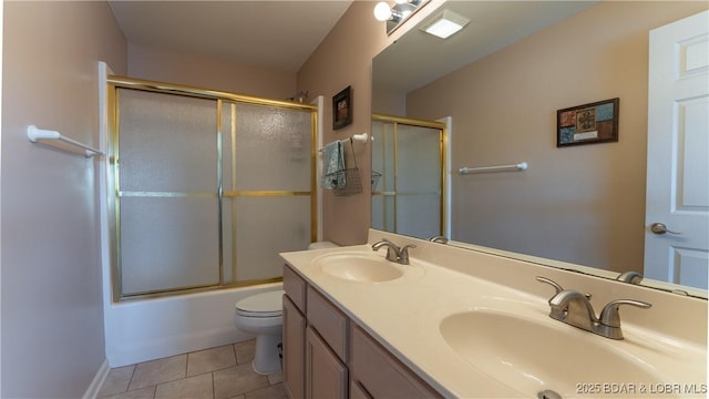 bathroom featuring tile patterned floors, double vanity, toilet, and a sink