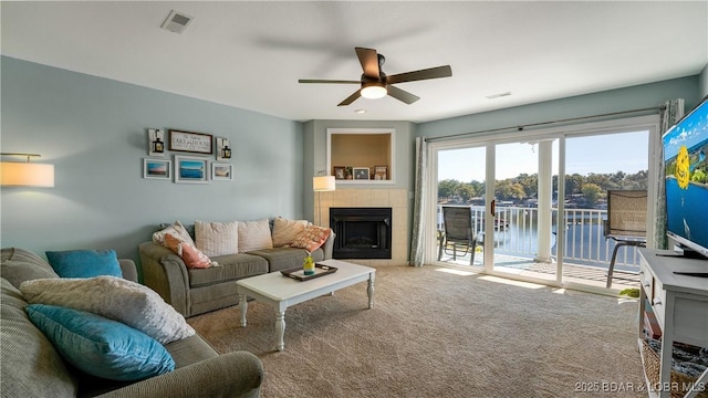 carpeted living room with a fireplace, visible vents, and ceiling fan