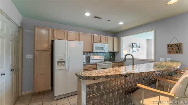 kitchen with visible vents, backsplash, a peninsula, light tile patterned flooring, and white appliances