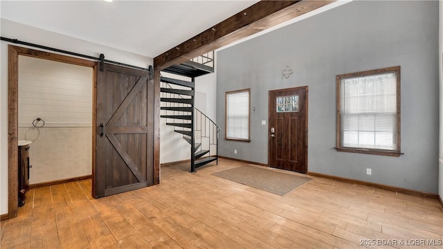 entrance foyer featuring a barn door, light hardwood / wood-style floors, and beam ceiling