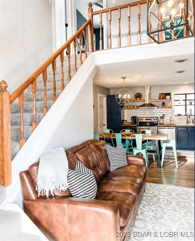 living room with a towering ceiling, sink, a notable chandelier, and light wood-type flooring