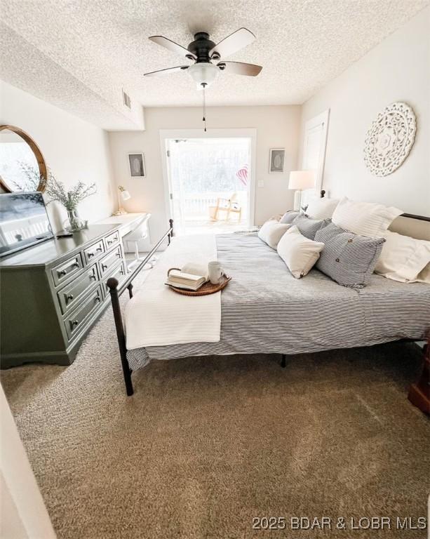 carpeted bedroom with ceiling fan and a textured ceiling