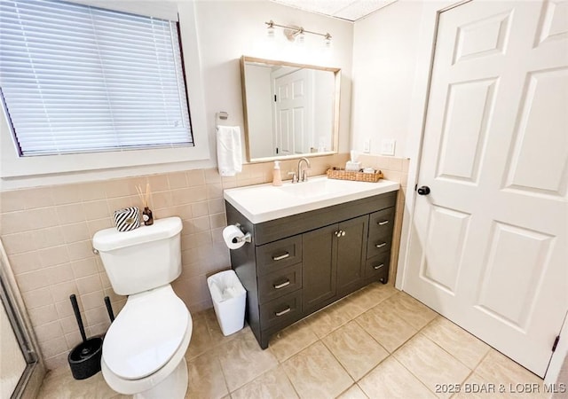 bathroom with vanity, tile patterned floors, toilet, and tile walls