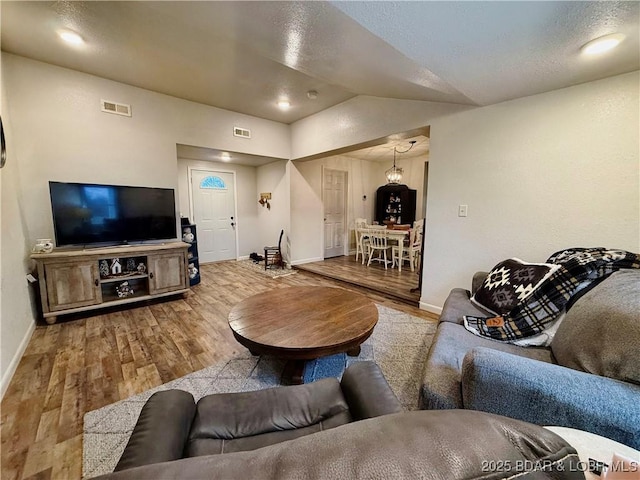 living room featuring wood-type flooring and vaulted ceiling