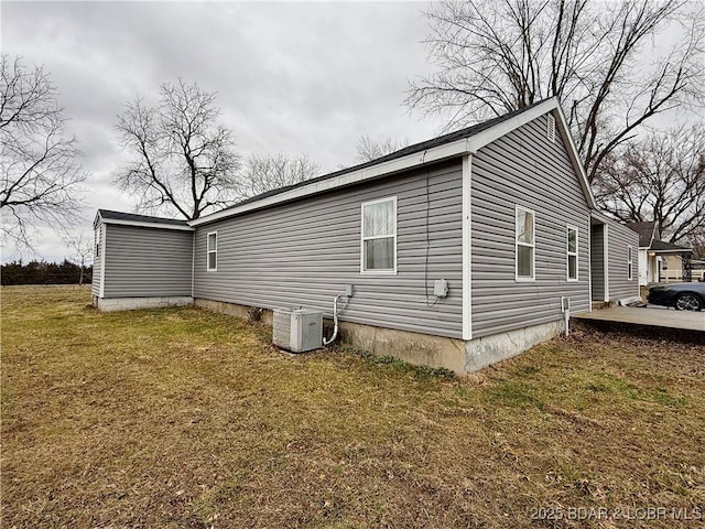 view of side of home featuring a lawn and central air condition unit