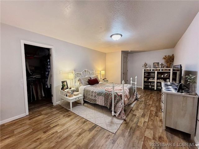 bedroom with hardwood / wood-style flooring, a spacious closet, and a textured ceiling