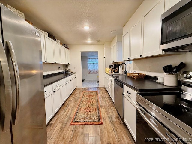 kitchen featuring white cabinetry, appliances with stainless steel finishes, sink, and light hardwood / wood-style flooring