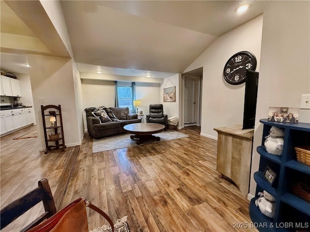 living room featuring lofted ceiling, light hardwood / wood-style flooring, and baseboard heating