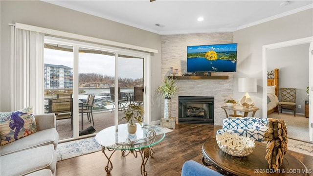 living room featuring visible vents, ornamental molding, wood finished floors, a large fireplace, and baseboards