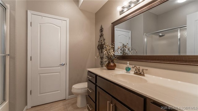 bathroom featuring vanity, a shower stall, and toilet