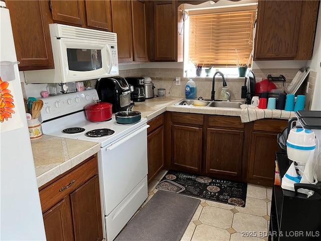 kitchen featuring sink, backsplash, and white appliances