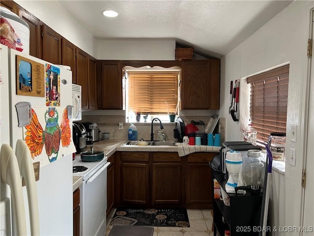 kitchen featuring lofted ceiling, dark brown cabinetry, sink, a textured ceiling, and white appliances