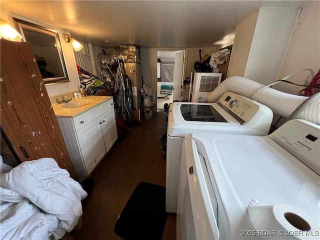 clothes washing area with dark wood-type flooring, washing machine and clothes dryer, and sink