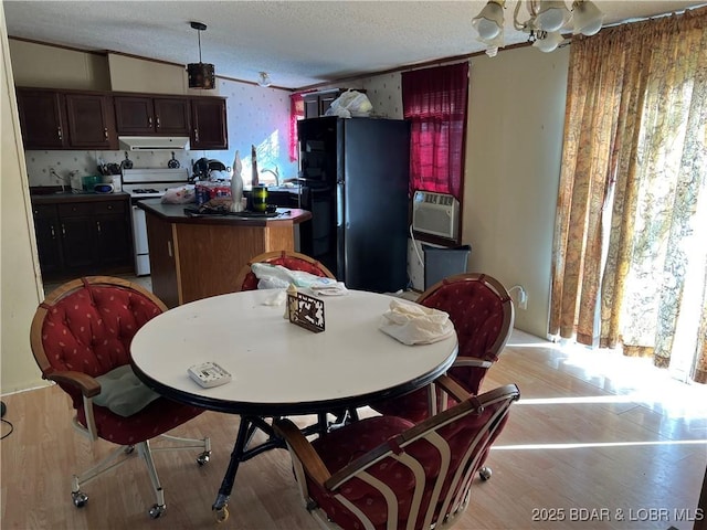 dining space with cooling unit, vaulted ceiling, a textured ceiling, and light wood-type flooring