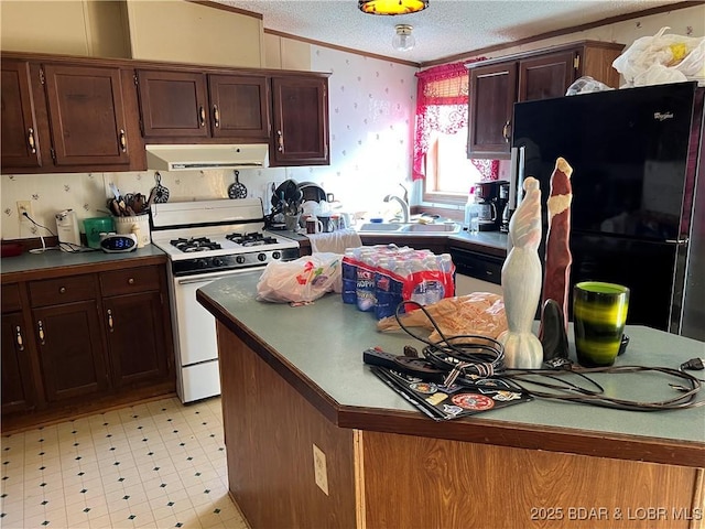 kitchen with sink, crown molding, a textured ceiling, black refrigerator, and white gas range