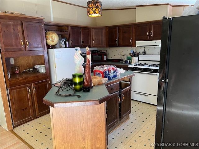 kitchen featuring decorative light fixtures, a textured ceiling, ornamental molding, a kitchen island, and white appliances