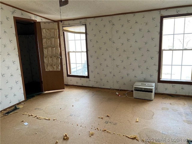 unfurnished room with crown molding, an AC wall unit, and a textured ceiling