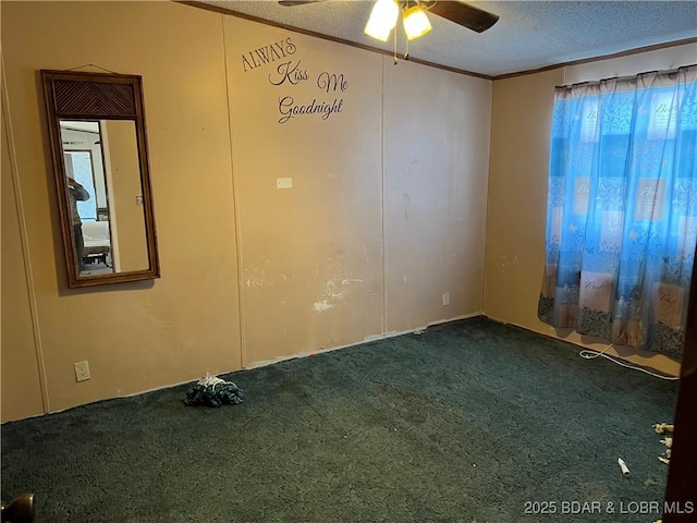 empty room featuring ceiling fan, dark carpet, ornamental molding, and a textured ceiling